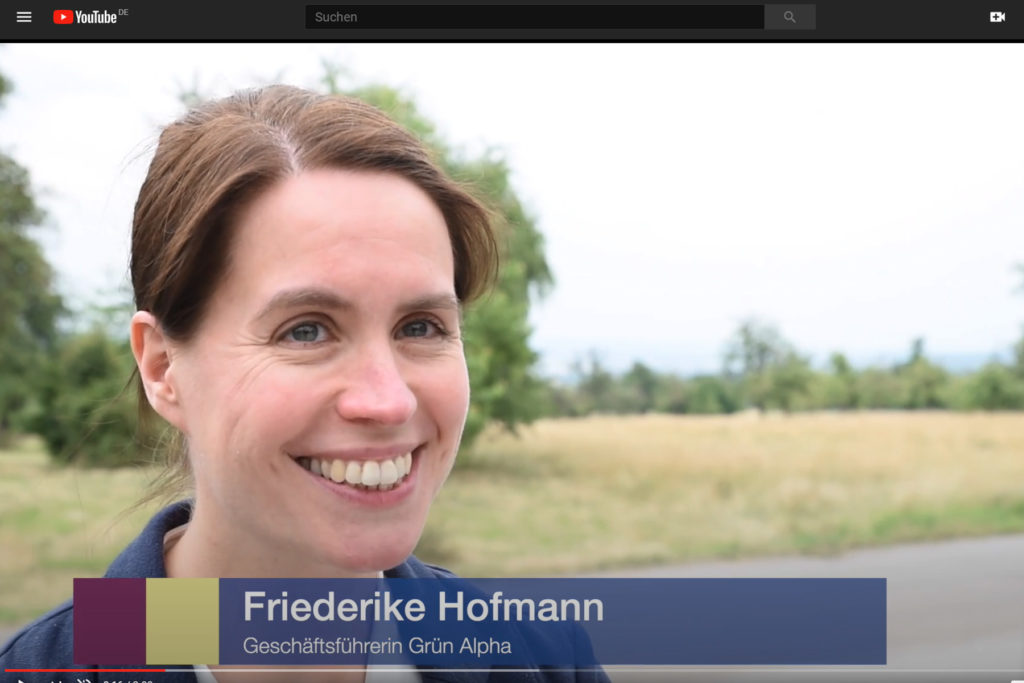 Lächelnde Friederike Hofmann in einem YouTube-Video mit der Bauchbinde: "Friederike Hofmann, Geschäftsführerin GRÜN alpha"