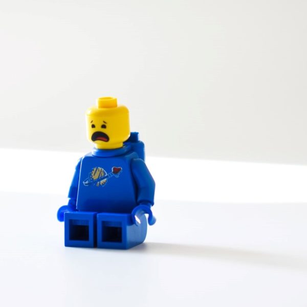 Auf einem weißen Tisch steht eine blaue Legofigur, bereit für die Spendensammlung.