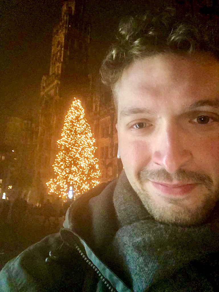 Ein Mann macht für Spendenzwecke ein Selfie vor einem Weihnachtsbaum.