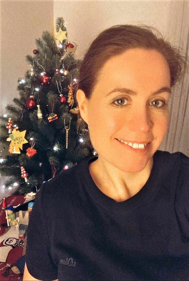 Eine Frau macht vor einem Weihnachtsbaum ein Spenden-Selfie.