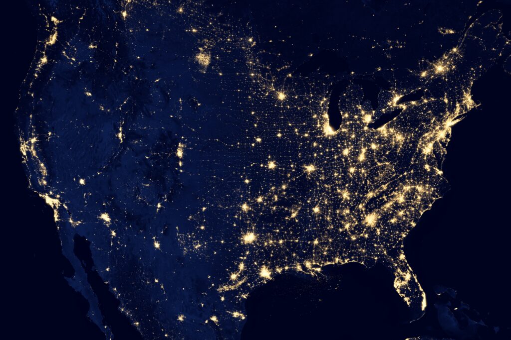 NASA-Satellitenbild der Vereinigten Staaten bei Nacht, das das faszinierende Zusammenspiel lebendiger Stadtlichter und beruhigender Naturlandschaften zeigt.
